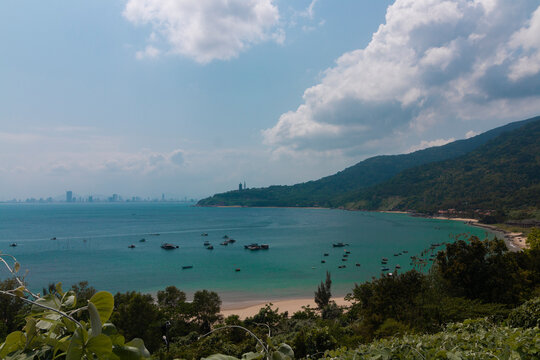 A shot from a viewpoint of fishing boats on the South China Sea surface and the Linh Ung Pagoda against a Da Nang cityscape by spring day
