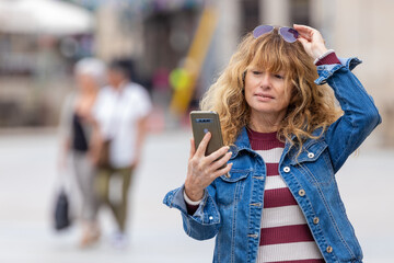 attractive adult woman on the street looking at mobile phone