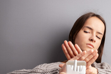 a teenager refuses cigarettes, a young woman shows with her hands stop nicotine