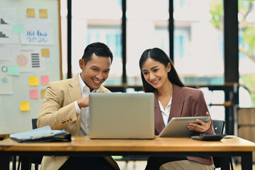 Male manager explaining information, discussing business plan with young female colleague