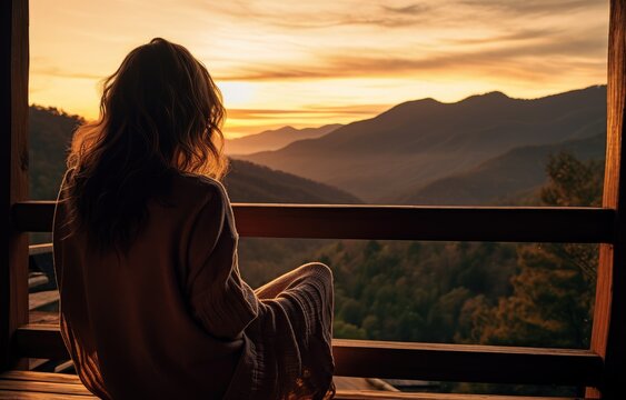 Woman Sitting On A Porch Overlooking A View Of The Hills