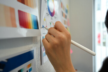 Closeup view of woman hand working with color palette, choosing color samples on whiteboard at graphic studio