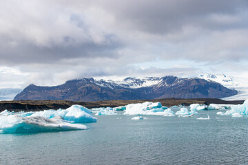 Ice floes in a glacial lake in Iceland with vulcano mountains in the background, the climate crisis...