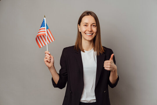 Studio portrait of a young smiling woman holding USA flag and a thumb up.