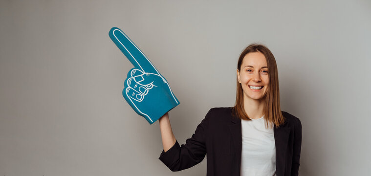 Banner size shot of a smiling woman wearing a fan glove and pointing aside.