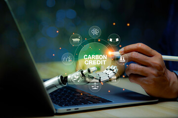 Businessman points at carbon credit icon in in robotic hand Green energy icon around it. Green...