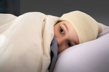 Angry child suffering cold complaining in a bed in winter