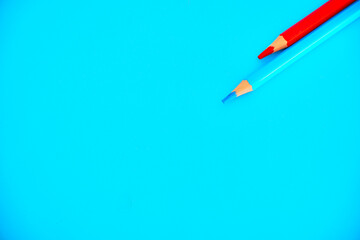 Fondo de color azul con dos lápices azul y rojo. Espacio para diseñar y poder escribir. 