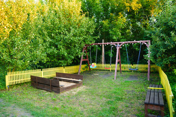 lawn with playground in the garden. sandbox, swings and benches.