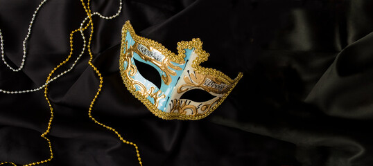 Christmas carnival mask on the on the black textile background. Top view. Copy space.
