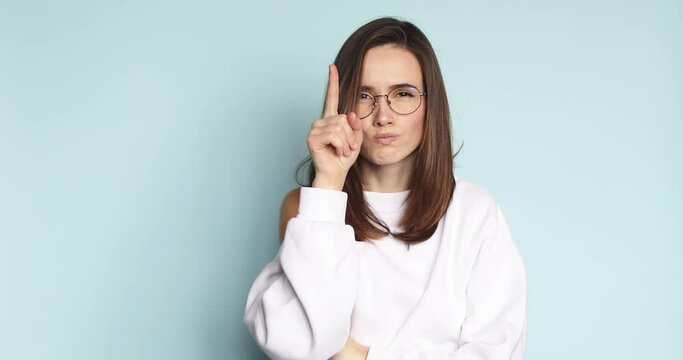 Serious woman in eyeglasses shaking finger gesturing no, looking dissatisfied, frowning and accusing with strict negative expression, be careful, choosing guilty on blue screen. I am warning you! 