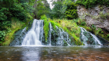 Crystal clear waterfall surrounded by greenery in the middle of the highlands of Scotland, UK.
