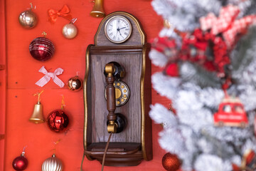 Red retro phone box with vintage wooden telephone is decorated with Christmas tree, balls. New Year holiday background.