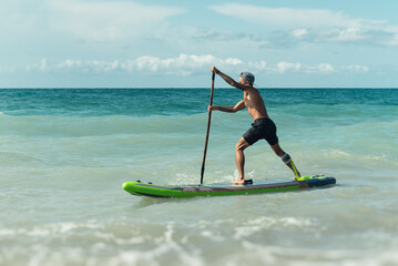 athletic wiry surfer guy swims with a paddle on a sup board in the sea