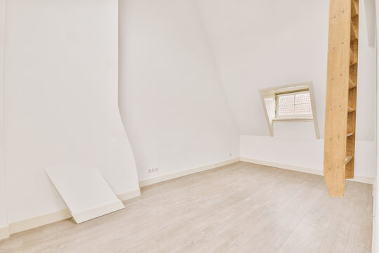 Empty mansard room with window and radiator