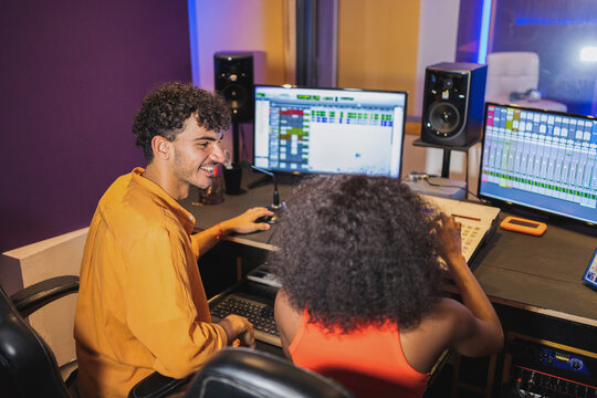 Happy man and black woman creating music in studio