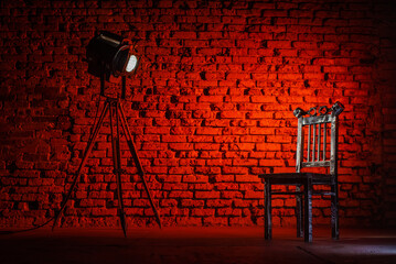 Iron chair in the lights of retro style theater spotlight on the brick wall background with copy...