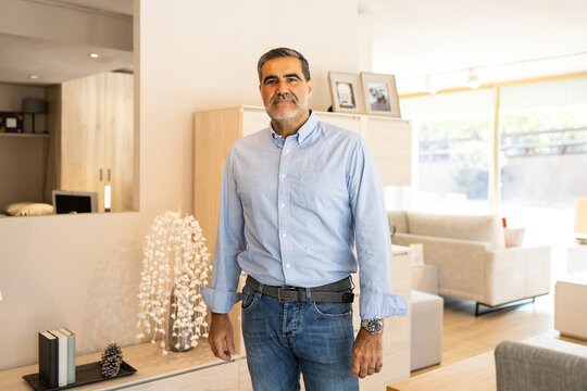 Mature man standing in furniture shop and looking at camera