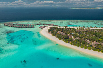 Stunning aerial landscape, luxury tropical resort with water villas. Beautiful island beach, palm trees, sunny sky. Amazing bird eyes view in Maldives, paradise coast. Exotic tourism, relax nature sea