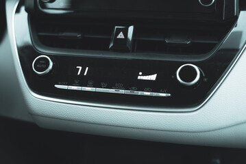 71-degree high temperature setting with knobs, digital display inside modern car, defrost mode with fan at full blast for defogger windshield windows