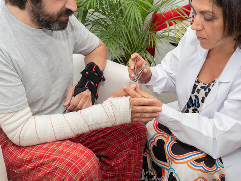 Woman trimming fingernails with nail clippers while helping injured husband man