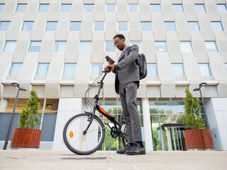 Black businessman with smartphone and bicycle