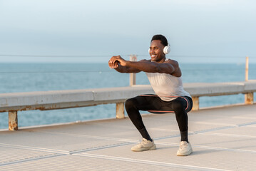 Focused black man squatting on embankment