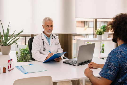 Mature man diagnosing anonymous black patient at appointment