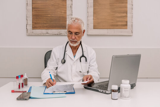 Senior man with laptop taking notes