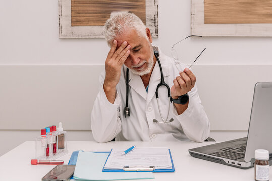 Senior doctor leaning on hand in hospital - Powered by Adobe