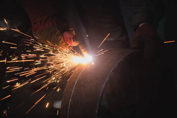 Welder cuts a metal pipe with a plasma cutter close up.