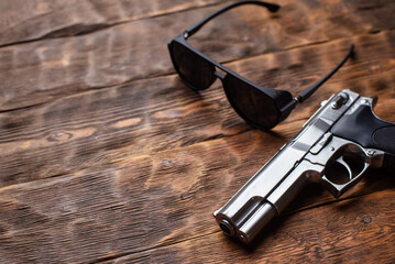 Toy gun and sunglasses on the detective wooden table top view background concept. Secret service. Spy desk background.