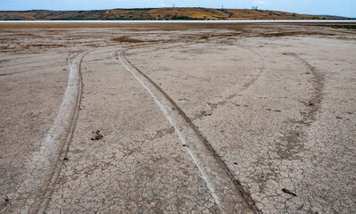 Traces of car tires on the cracked dried muddy bottom of the Kuyalnik estuary, Ukraine