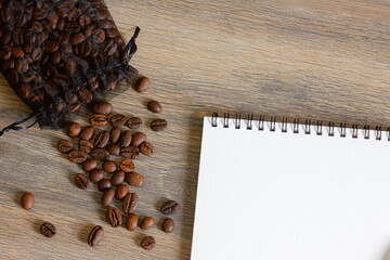 Notepad and coffee beans scattered on the wooden table