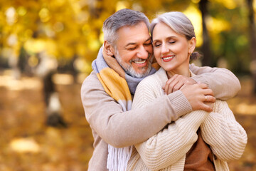 Fototapeta premium Beautiful smiling senior family couple husband and wife looking at camera with love in park on autumn day.