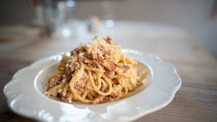 Spaghetti Carbonara lunch on white plate and blurry background, side view