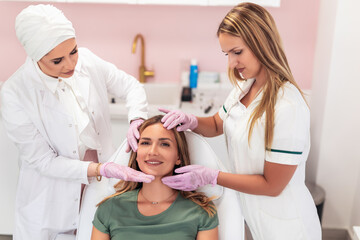 Young pretty woman came to a beauty salon and consults with a beautician on anti-aging treatments.