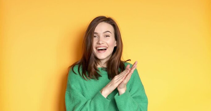 Young woman applauding after presentation in a conference isolated on yellow background. Applauding girl is very glad and happy, she claps hands because of excellent news, support. 