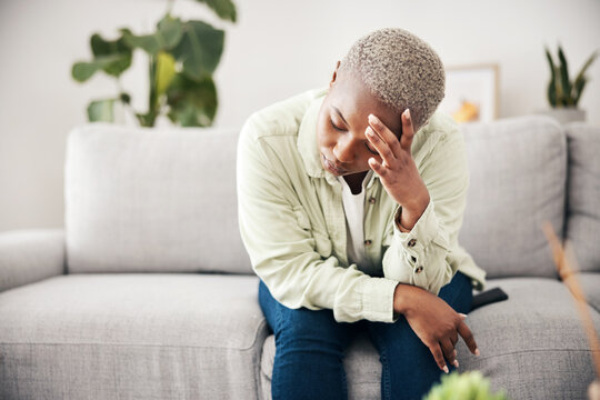 Woman, depression and headache in home for anxiety, mental health and stress of mistake, debt or crisis. Tired, sad and frustrated african person with emotional trauma, broken heart and worry on sofa