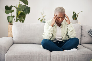 Stress, headache and burnout with a black woman on a sofa in the living room of her home for mental health. Anxiety, pain or vertigo and a young person in an apartment with depression or a migraine