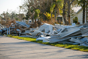 Heaps of debris rubbish on street side near severely damaged by hurricane houses in Florida mobile...