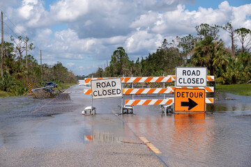 Hurricane flooded street with road closed signs blocking driving of cars. Safety of transportation...