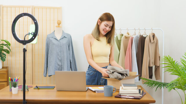Online selling concept, Fashion designer packing clothes into parcel box to delivery sending client