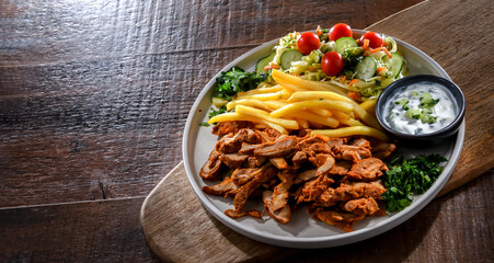 Kebab served with french fries, vegetable salad and tzatziki