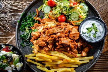 Kebab served with french fries, vegetable salad and tzatziki