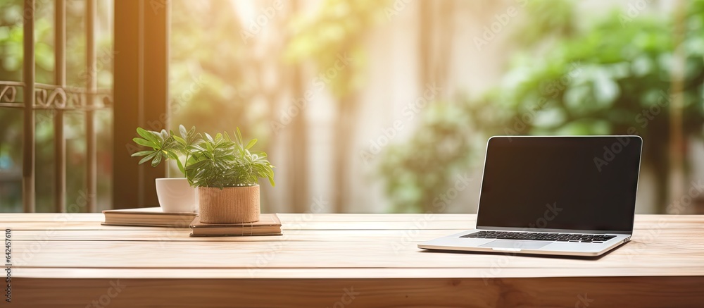 Poster Blurred office background with a wooden desk laptop wireless mouse graphics tablet and notebook