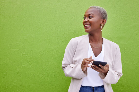 Woman, Thinking And Phone For Communication By A Wall Or Green Background With Internet. Happy African Female Person Outdoor With A Smartphone For Social Media, Networking App And Chat Mockup Space