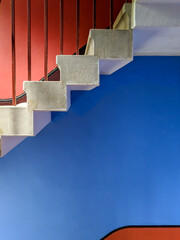 White steps leading upwards in front of a a bright red and blue painted wall.