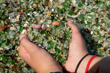 Hands holding small crystals on the beach