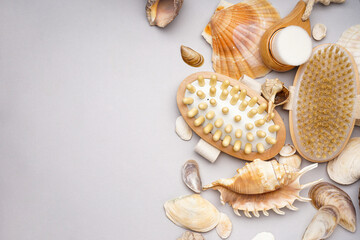Many beautiful sea shells and massage brush on grey background, space for text. Top view.